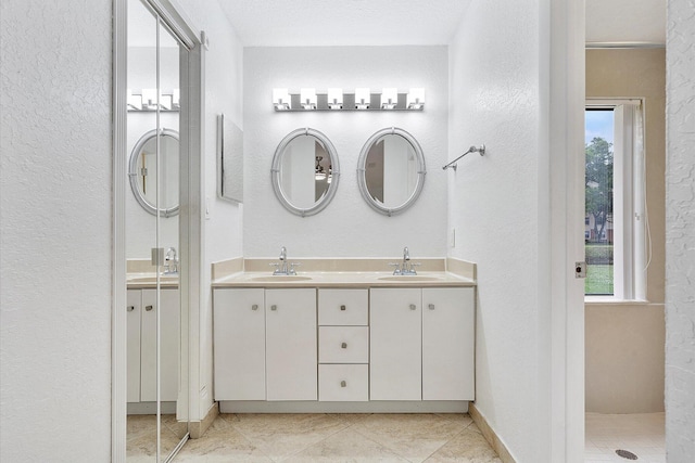 bathroom with a textured ceiling, vanity, a healthy amount of sunlight, and walk in shower