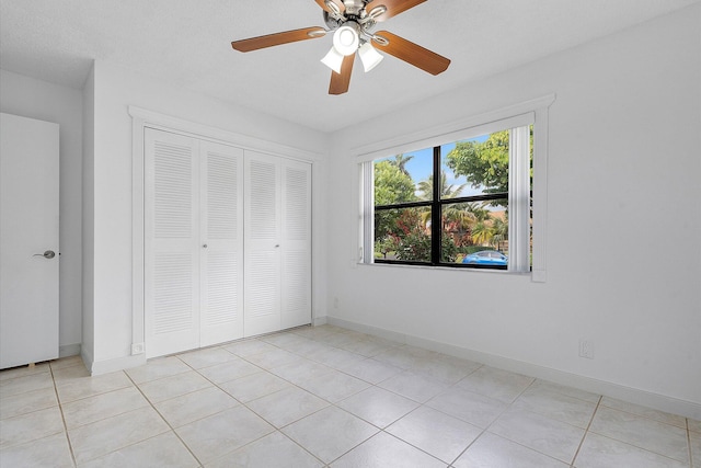 unfurnished bedroom with ceiling fan, a closet, and light tile patterned floors