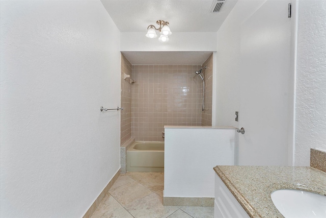 bathroom with tile patterned floors, vanity, and tiled shower / bath