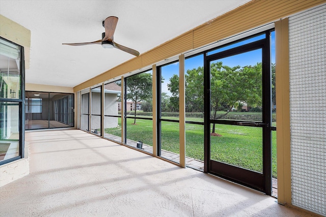 unfurnished sunroom with ceiling fan