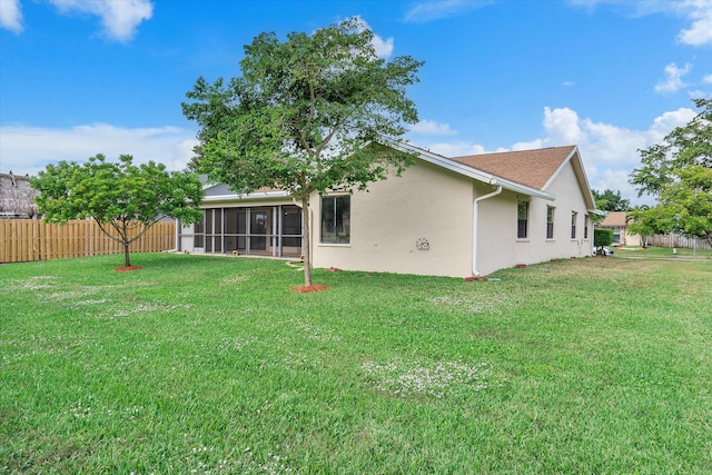 rear view of house featuring a lawn and a sunroom