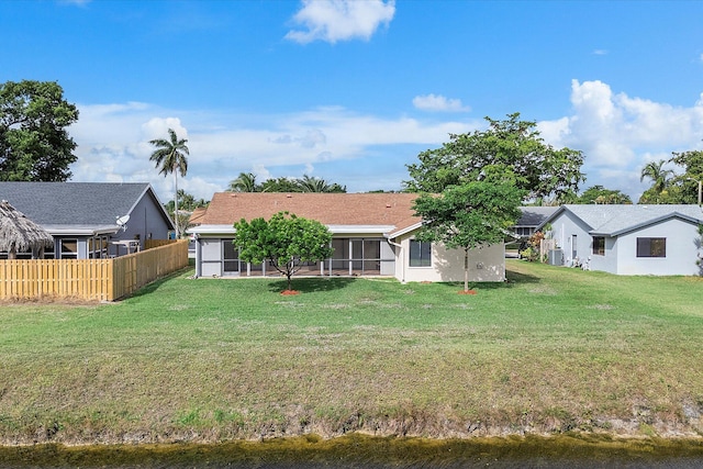 rear view of house with a sunroom and a yard