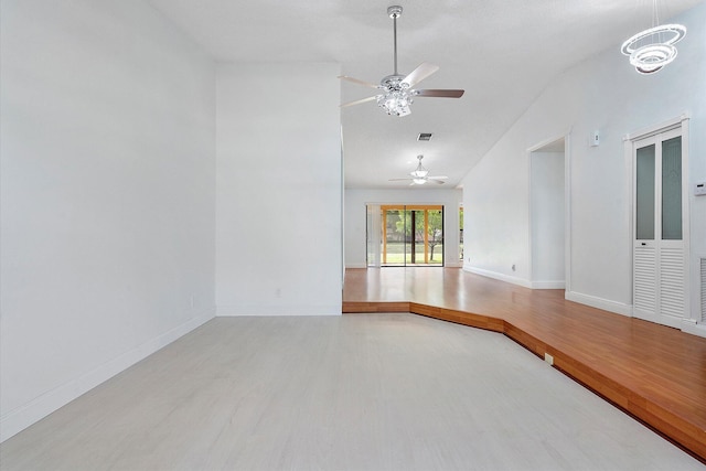 empty room with wood-type flooring, ceiling fan with notable chandelier, and vaulted ceiling