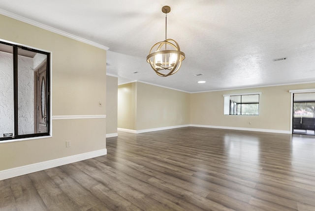 spare room with a textured ceiling, a notable chandelier, dark hardwood / wood-style flooring, and crown molding