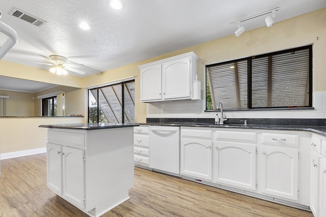 kitchen featuring ceiling fan, dishwasher, track lighting, a textured ceiling, and white cabinets