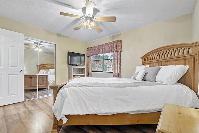 bedroom with ceiling fan, wood-type flooring, a textured ceiling, and a closet