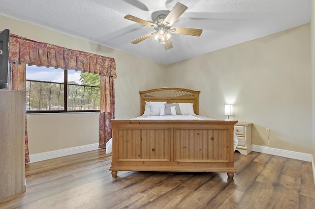 bedroom featuring hardwood / wood-style flooring, ceiling fan, and a textured ceiling