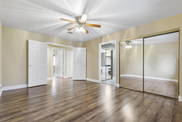 unfurnished bedroom with ceiling fan, dark hardwood / wood-style flooring, and a textured ceiling