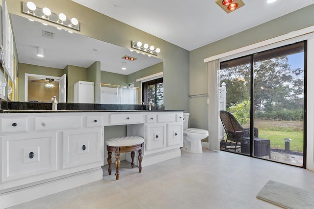 bathroom featuring ceiling fan, toilet, a shower with shower door, and vanity