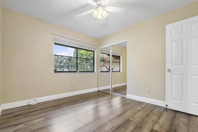 unfurnished bedroom with ceiling fan, dark hardwood / wood-style floors, a textured ceiling, and a closet