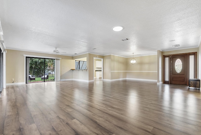 unfurnished living room with wood-type flooring, ceiling fan with notable chandelier, a textured ceiling, and crown molding