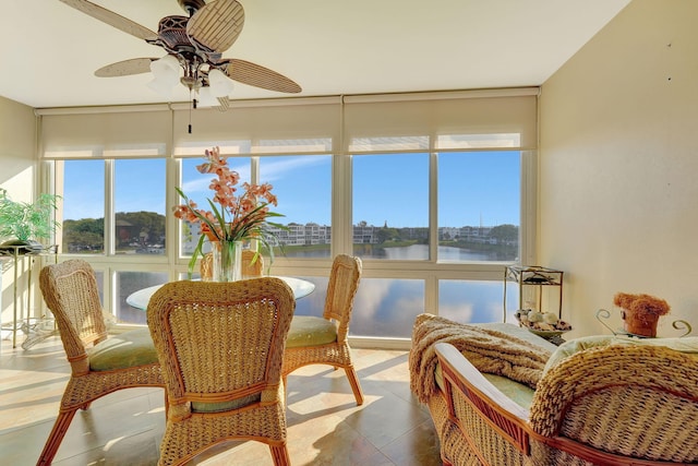 sunroom with ceiling fan and a water view