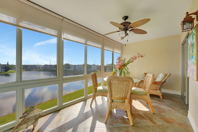 sunroom / solarium with ceiling fan and a water view