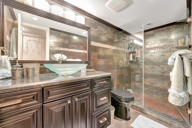 bathroom featuring vanity, toilet, ornamental molding, tile walls, and a shower with shower door