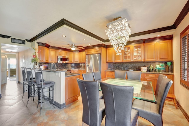 kitchen featuring appliances with stainless steel finishes, a center island with sink, ornamental molding, and a kitchen breakfast bar