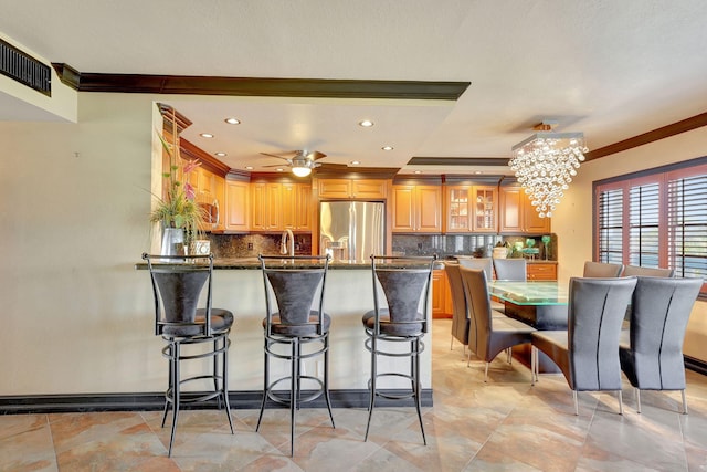 kitchen with decorative backsplash, stainless steel refrigerator with ice dispenser, ceiling fan with notable chandelier, and crown molding