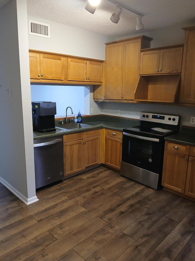 kitchen with dark hardwood / wood-style flooring, sink, track lighting, exhaust hood, and stainless steel appliances