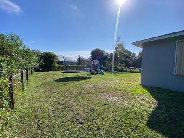 view of yard featuring a playground and a trampoline