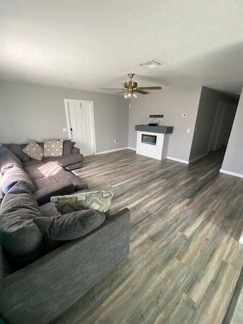 living room with a textured ceiling, hardwood / wood-style flooring, and ceiling fan