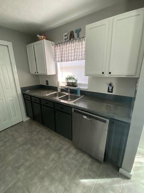 kitchen with a textured ceiling, white cabinetry, stainless steel dishwasher, and sink