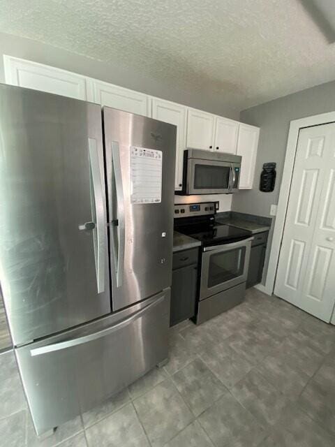 kitchen featuring a textured ceiling, white cabinetry, and stainless steel appliances