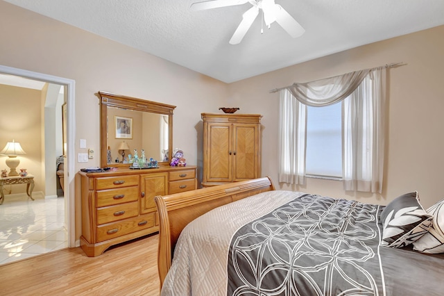 bedroom with a textured ceiling, ceiling fan, and light wood-type flooring