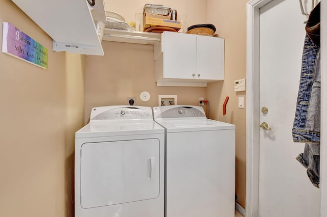 clothes washing area featuring cabinets and independent washer and dryer