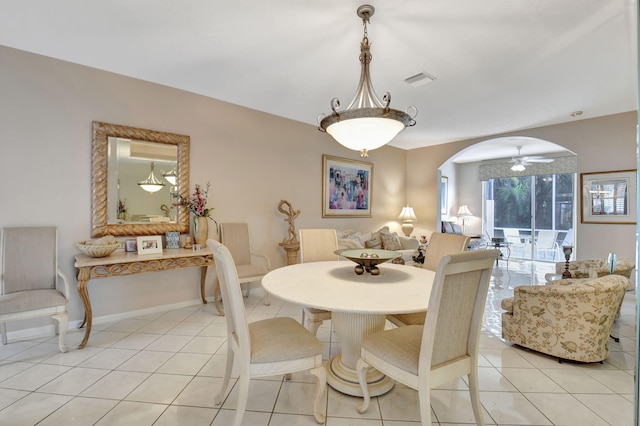 dining area featuring light tile patterned floors, baseboards, visible vents, and arched walkways