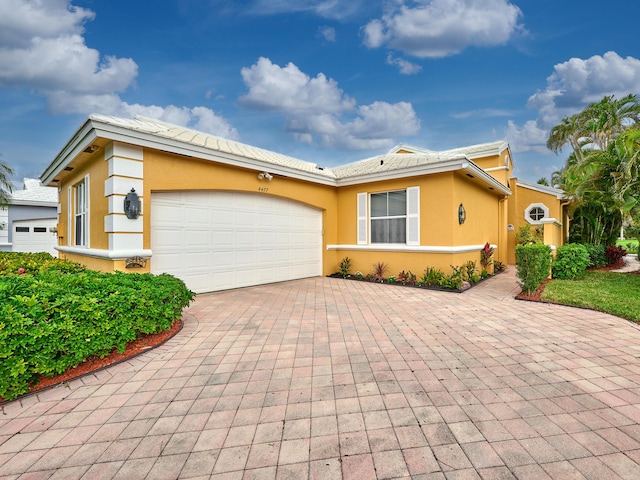 view of front facade featuring stucco siding, decorative driveway, and a garage