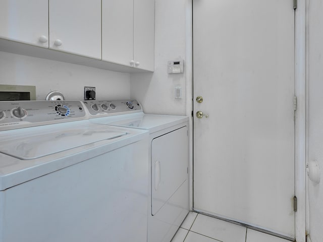 laundry room with cabinets, light tile patterned flooring, and washing machine and dryer