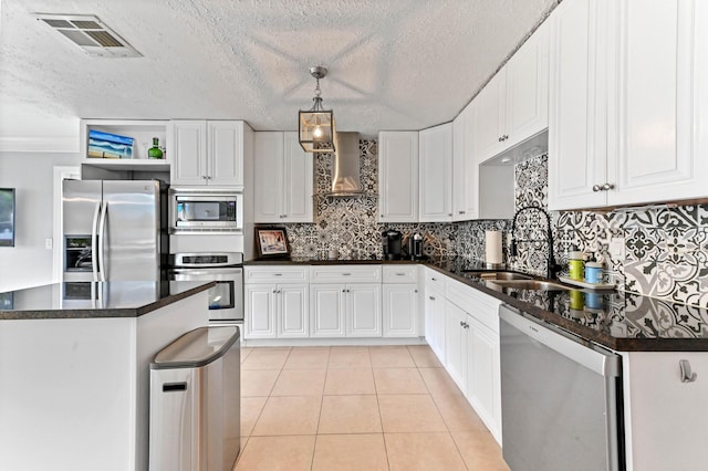 kitchen with appliances with stainless steel finishes, wall chimney exhaust hood, decorative light fixtures, and white cabinets