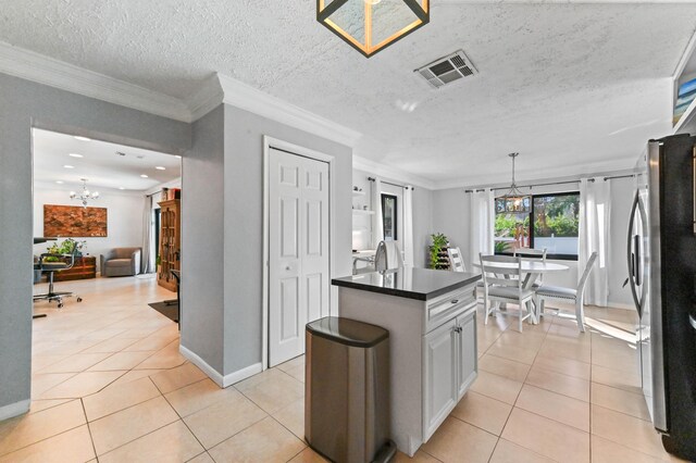 kitchen featuring appliances with stainless steel finishes, wall chimney range hood, white cabinets, and decorative light fixtures