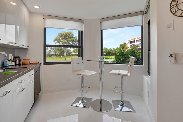 kitchen featuring stainless steel dishwasher, white cabinetry, and sink