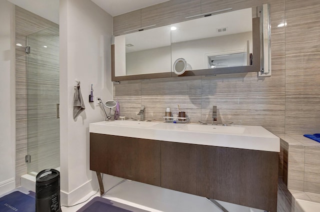 bathroom featuring vanity, a shower with shower door, backsplash, and tile walls