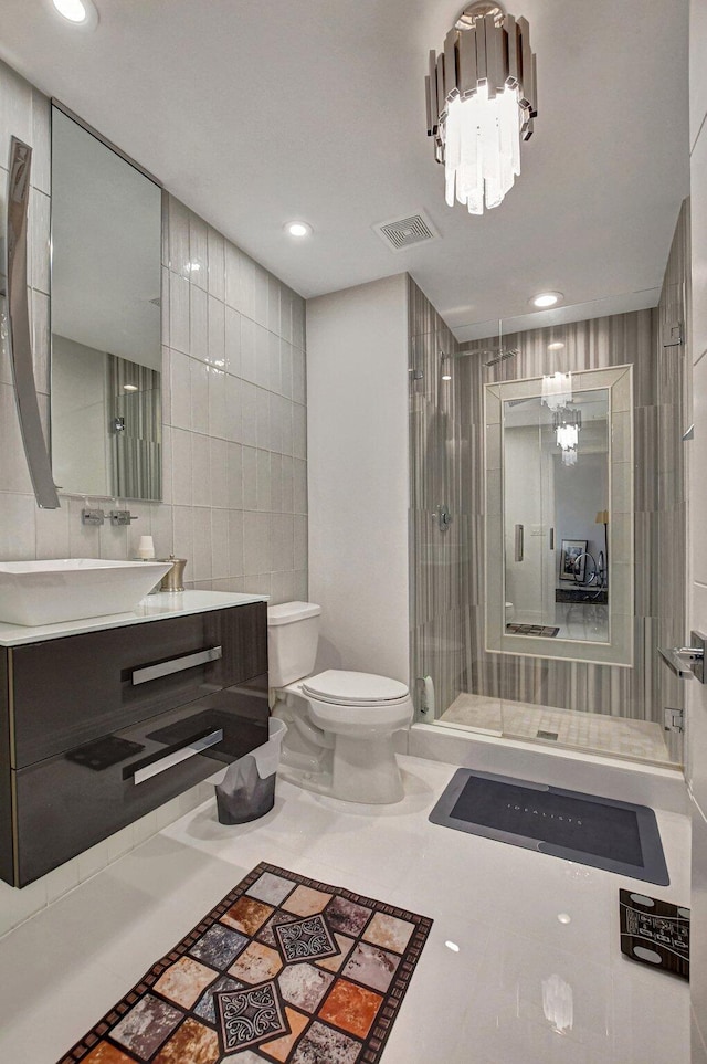 bathroom featuring vanity, toilet, tile walls, walk in shower, and a notable chandelier