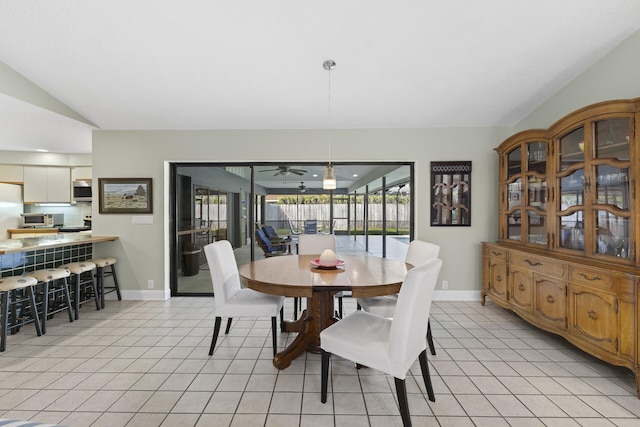 dining area with ceiling fan, light tile patterned floors, and vaulted ceiling