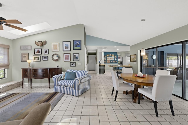 dining space featuring light tile patterned floors, lofted ceiling with skylight, and ceiling fan