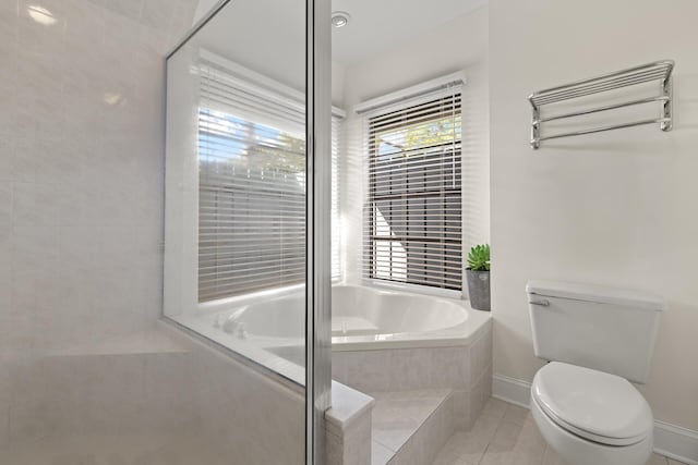 bathroom featuring tile patterned floors, toilet, and tiled bath