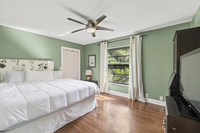 bedroom with ceiling fan, dark wood-type flooring, and a textured ceiling