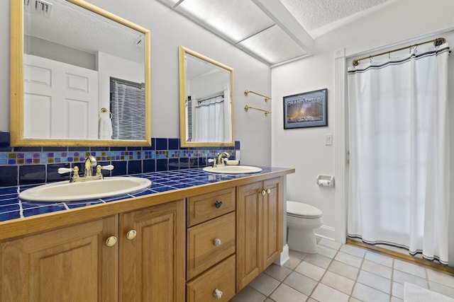 bathroom with vanity, tile patterned floors, decorative backsplash, toilet, and a textured ceiling