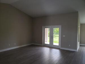 spare room with french doors, dark hardwood / wood-style floors, and vaulted ceiling