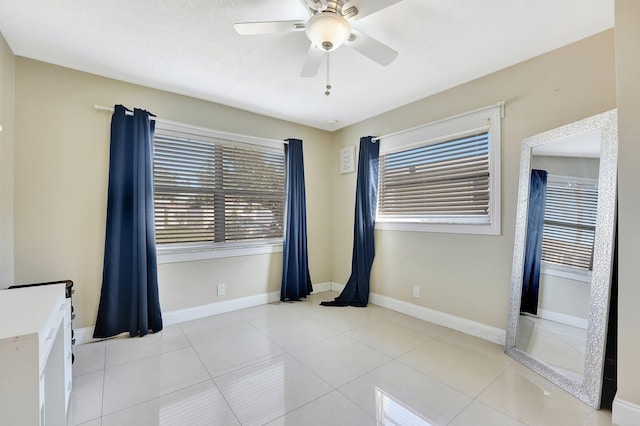 spare room featuring light tile patterned floors, ceiling fan, and a healthy amount of sunlight