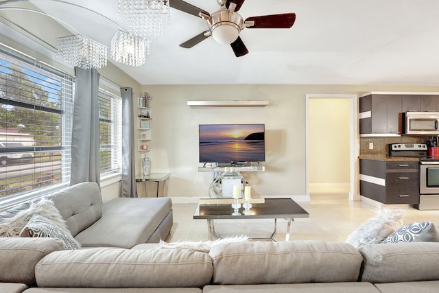 tiled living room with ceiling fan with notable chandelier