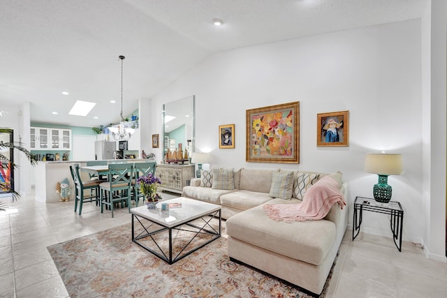 living room with vaulted ceiling with skylight, a notable chandelier, and light tile patterned floors