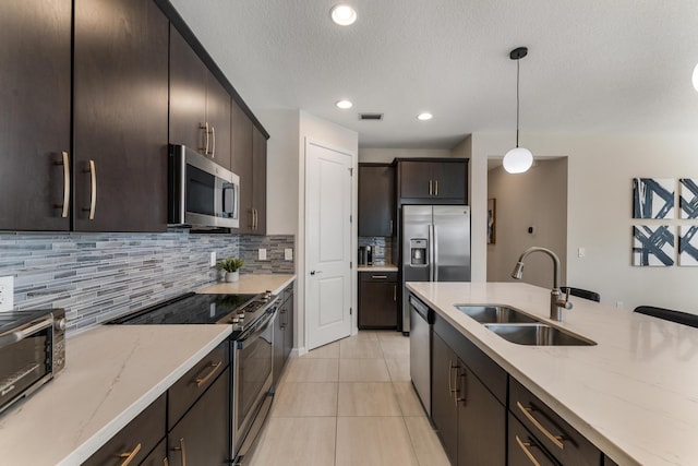 kitchen featuring pendant lighting, appliances with stainless steel finishes, sink, and light stone counters