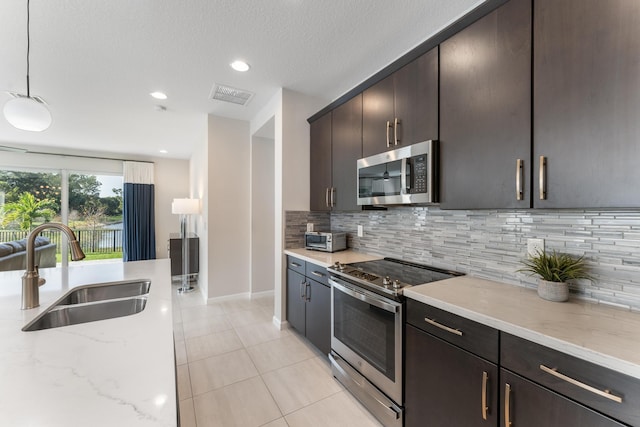 kitchen featuring pendant lighting, sink, backsplash, stainless steel appliances, and light tile patterned flooring