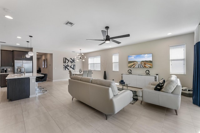 living room with sink, light tile patterned floors, plenty of natural light, and ceiling fan with notable chandelier