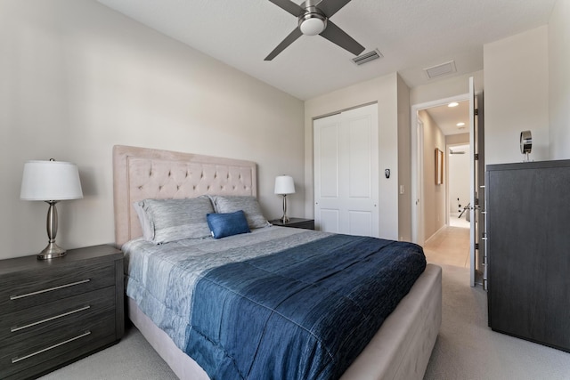 bedroom featuring light colored carpet, ceiling fan, and a closet