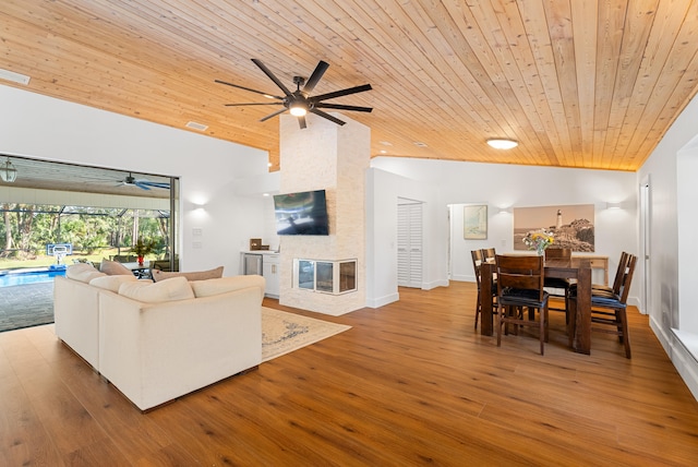 living room featuring wood-type flooring, vaulted ceiling, a fireplace, and wood ceiling