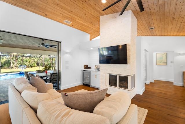 living room featuring wood ceiling, beverage cooler, a stone fireplace, and hardwood / wood-style floors